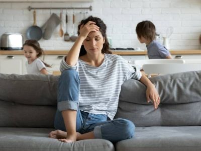 Parent assis sur un canapé pendant que les enfants jouent derrière