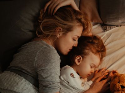 Un parent et un enfant blottis ensemble dans un lit; la parentalité positive peut aider les enfants à surmonter leurs difficultés de sommeil.