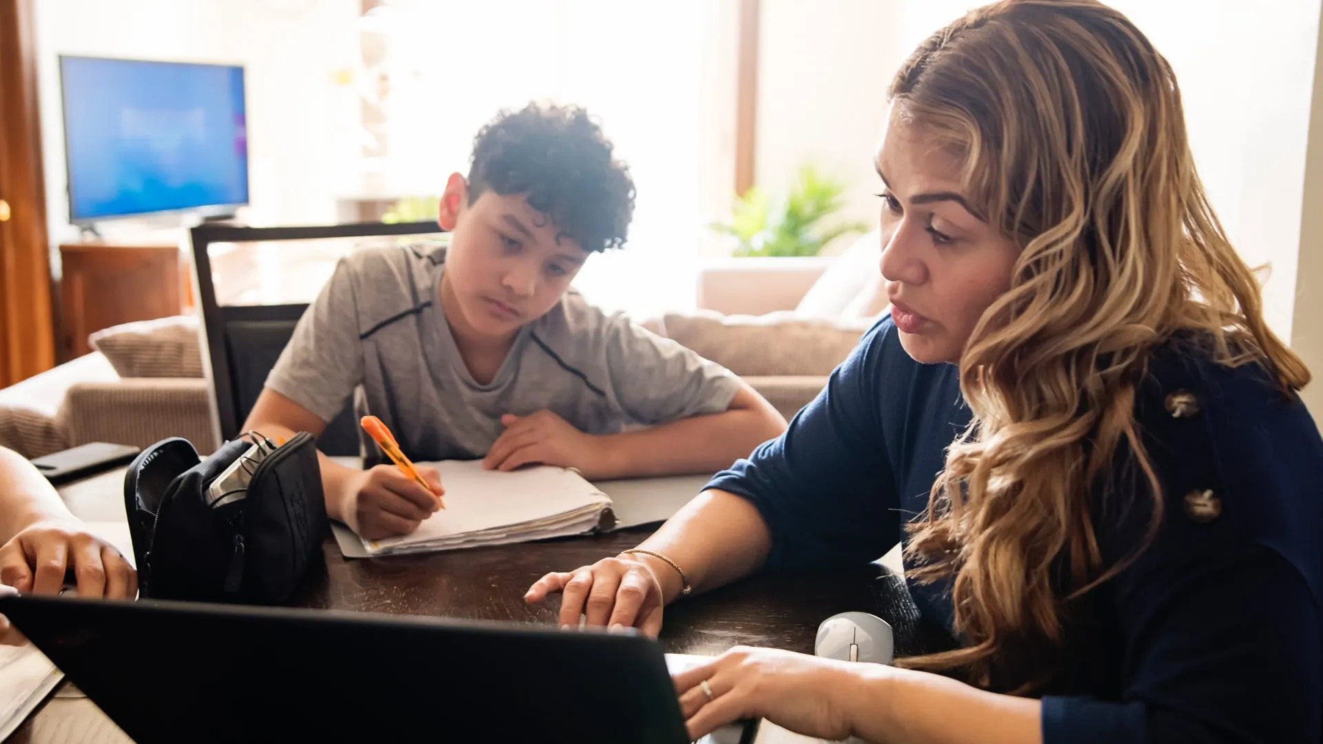 Parent assisting child with homework on a laptop