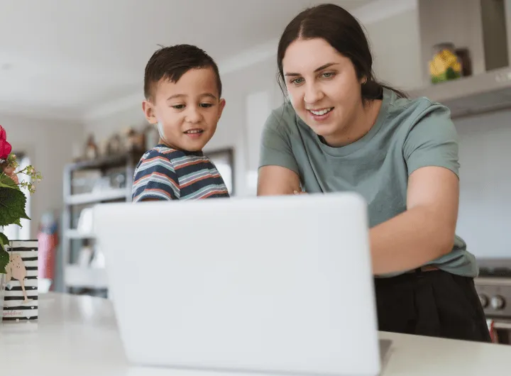 Parent and child using a laptop together in the kitchen